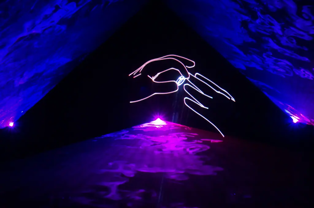 Laser-Linienzeichnung einer Hand, die einen Ring ansteckt, zwischen blauen und violetten Lichtflächen